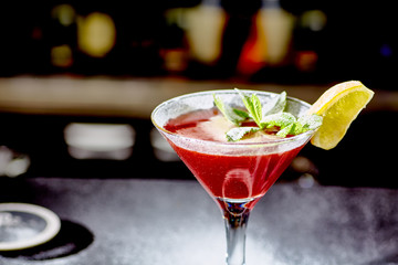 Red cocktail similar to a Margarita covered with powdered sugar is on the bar.