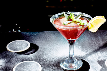 Red cocktail similar to a Margarita covered with powdered sugar is on the bar.