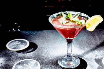 Red cocktail similar to a Margarita covered with powdered sugar is on the bar.
