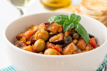 Traditional sicilian eggplant dish Caponata in bowl on concrete background. Selective focus.