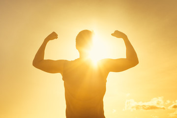 Strong man flexing in the sunshine. Strength, fitness and determination. 