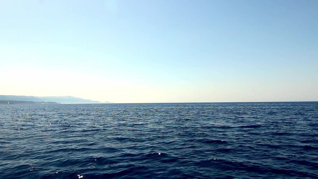 Port side view from water boating through Mediterranean Sea ripple ocean wake Sardinia Sardegna Italy