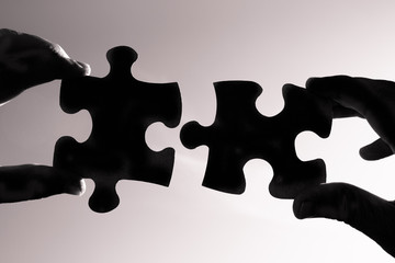 Hand connecting puzzle pieces together. 