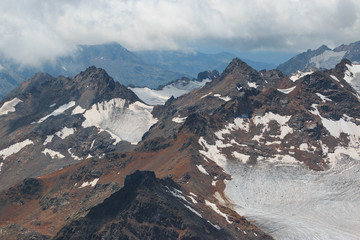 Caucasus mountains near Elbrus volcano with glaciers, clouds and peaks.