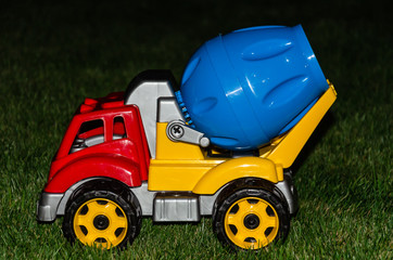 Children's toy concrete mixer. Colored plastic baby car on grass background. Car Models. Kids toys....
