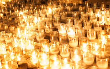 Rows of candles glowing in the dark. 