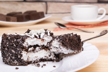 Sponge cake with souffle and chocolate chips, a piece on a fork, a cup of tea, chocolates