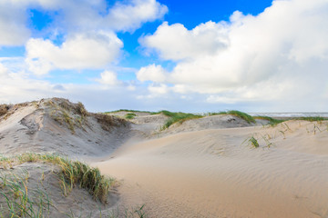 Newly formed Dunes on Dutch North Sea coast at IJmuiderslag with wind sweeping stripes in the sand  against the background of blue sky with scattered clouds