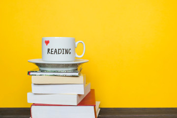White cup with words Love reading and books on the yellow background.
