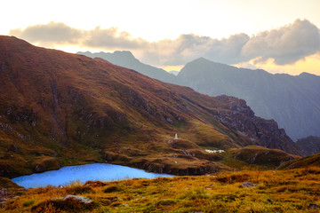 Fototapeta premium sunrise on Fagaras mountain ridges over the Capra glacier lake, Romania