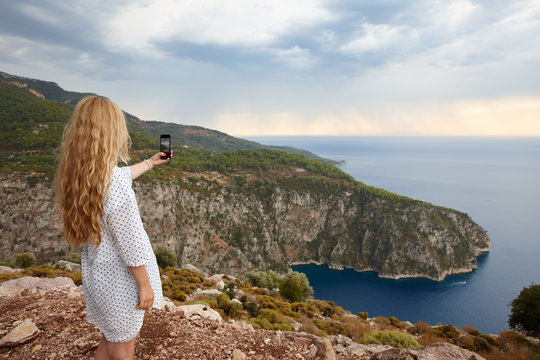 Young woman making phone pictures of sea landscape