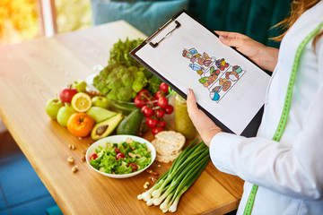 Holding schematic meal plan for diet with various healthy products on the background. Weight loss...