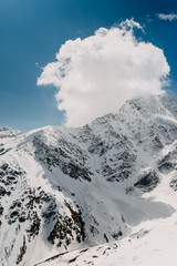 Close-up of towering sharp snowy mountain peaks with clouds