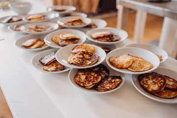 Many plates with sweet pancakes on a white tree
