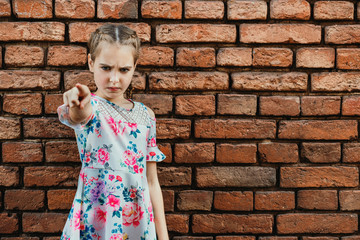 Angry teenager girl on brick wall background