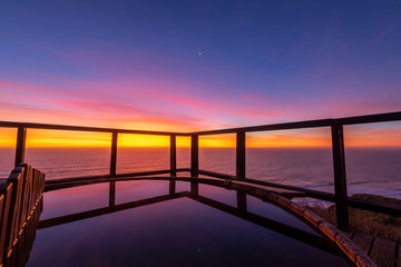 An amazing an idyllic view a wooden hot tub waiting us for some relaxation time during sunset and twilight before an awe night sky with a small crescent moon. A leisure activity at Chilean coastline