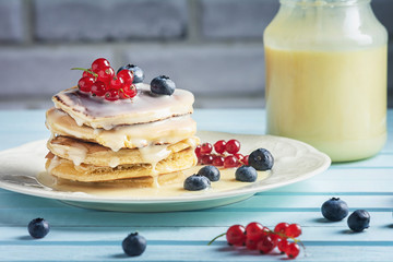 Pancakes with condensed milk are decorated with berries. Tasty breakfast.