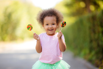 little African American girl in the summer on a walk smiling holding colorful candies