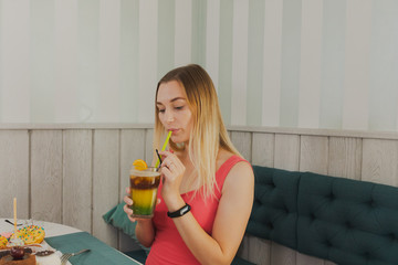 Girl in a cafe drinks sweet desserts with a drink.