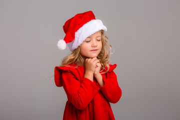 little girl the blonde smiles in a Santa hat on slalom background