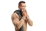 Young man with a scarf sneezing and blowing nose