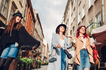 Girls talking and having fun. Outdoor shot of three young women walking on city street.
