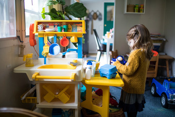 A little girl in a play kitchen