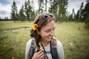 Closeup of young women smiling with flower in hair with field behind