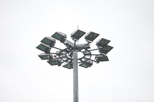 Lighting pole with halogen floodlight and  lightning conductor on the top of it. Metal construction with illuminator. Lighting coverage of a large area. City and urban illumination.