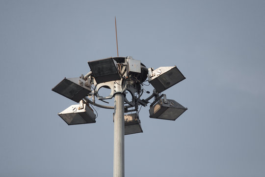 Lighting pole with halogen floodlight and  lightning conductor on the top of it. Metal construction with illuminator. Lighting coverage of a large area. City and urban illumination.
