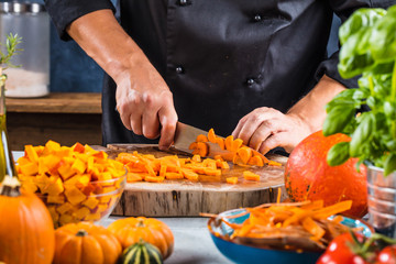 Chef cutting fresh and delicious pumkin and vegetables for cooking soup