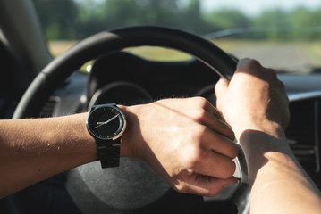 Driver is checking a time on wrist watch on his hand.