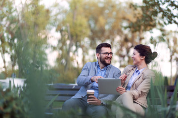 Business people using tablet device while sitting in park