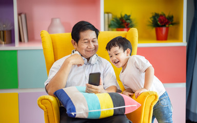 Happiness Asia grandfather  and grandson playing game in living room at home