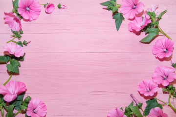 Fototapeta na wymiar pink flowers with green leaves light pink tree background. wood texture background. top view background