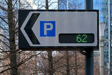 Traffic sign board showing number of parking spaces and arrow pointing to park lot, text can be...