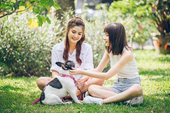 two  Asian female chit chat time and play a dogs in garden