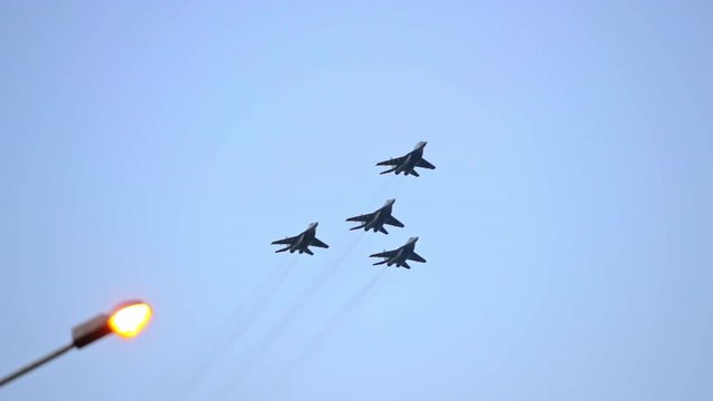 Column of four military warplanes flies over the ground. Military helicopters and planes in the evening sky. Air force parade. Independence Day parade in the CIS country. Belarus 3 July 2019.