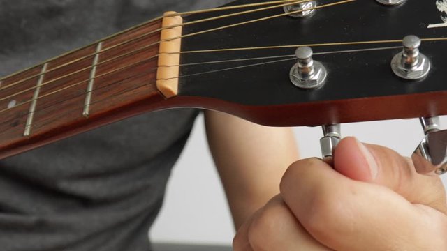extreme focus of  hand movement of man tuning his guitar.J.A