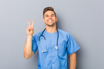 Young nurse man showing number two with fingers.