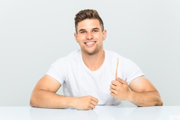 Young man holding a toothbrush happy, smiling and cheerful.