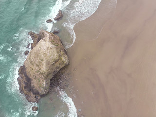 Beach landscape top view, sand, road and rock in the water. Sand, ocean texture with waves