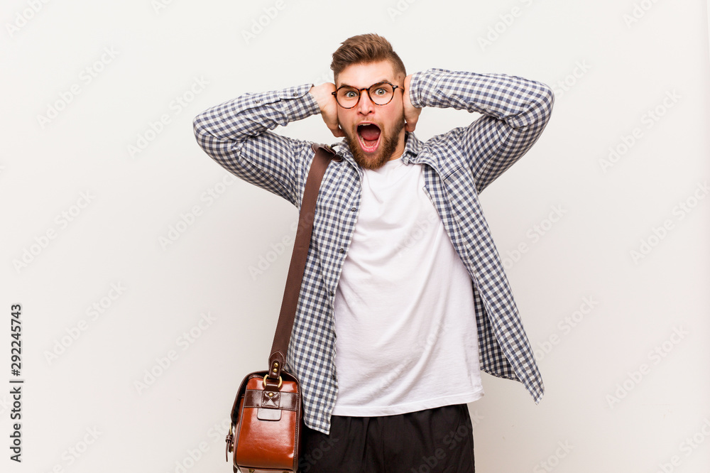 Wall mural Young modern business man covering ears with hands trying not to hear too loud sound.