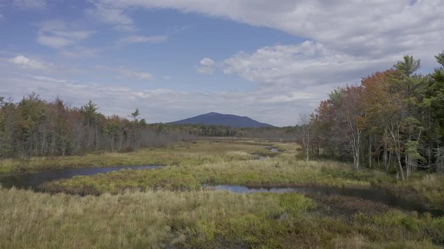 Aerial 4K video rising up over marsh with view of fall foliage and Mount Monadnock in New Hampshire