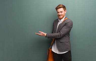 Young redhead business man holding something with hands