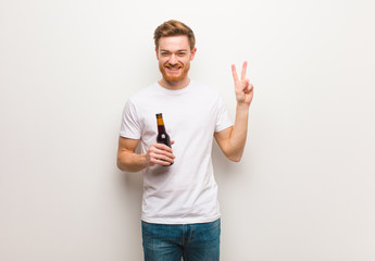 Young redhead man. Holding a beer.