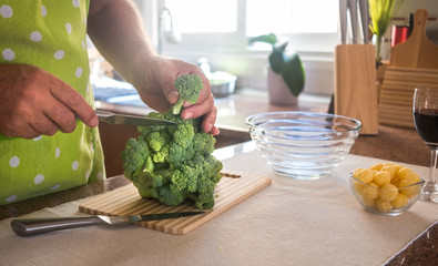 An old man's hands cleaning and cutting broccoli. Vegetarian and healthy food