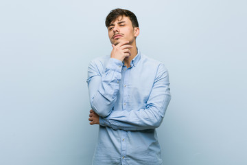 Young hispanic business man looking sideways with doubtful and skeptical expression.