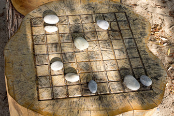 outdoor chess board with stone game pieces on a beach made from a tree stump