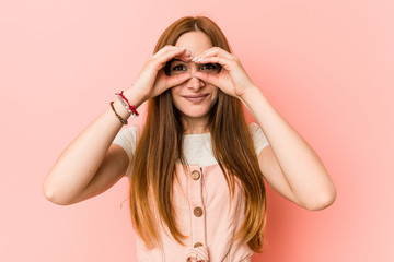 Young ginger woman with freckles showing okay sign over eyes